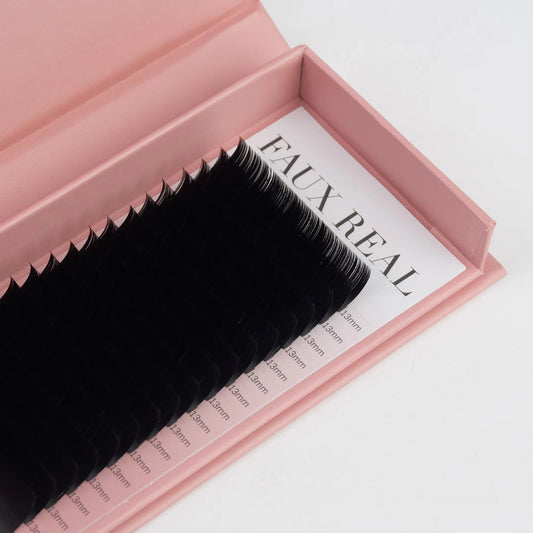 False eyelashes in a pink box with 'FAUX REAL' branding on a white background